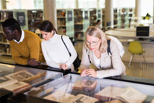 Student observing rare books in cases